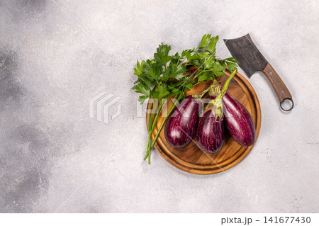 Fresh eggplants and parsley on a wooden board Fresh eggplants and parsley on a wooden board 141677430