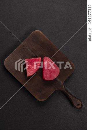 Fresh raw tuna steaks preparing on wooden board Fresh raw tuna steaks preparing on wooden board 141677550