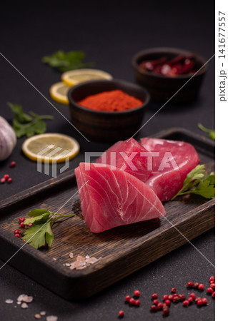 Raw tuna steaks preparing with spices and lemon slices 141677557