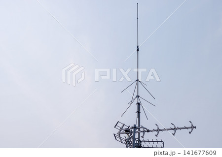 Television antenna and telecommunication receiver mast mounted against a clear daytime sky. High Quality Photo Television antenna and telecommunication receiver mast mounted against a clear daytime sky. High Quality Photo 141677609