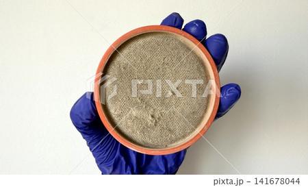 Dirty Round Air Filter Held in Gloved Hand for Maintenance and Replacement Dirty Round Air Filter Held in Gloved Hand for Maintenance and Replacement 141678044