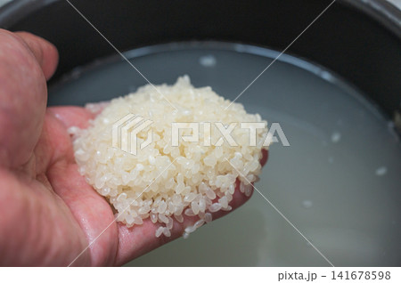 研いだお米を手に、炊飯前の白米のクローズアップ 研いだお米を手に、炊飯前の白米のクローズアップ 141678598