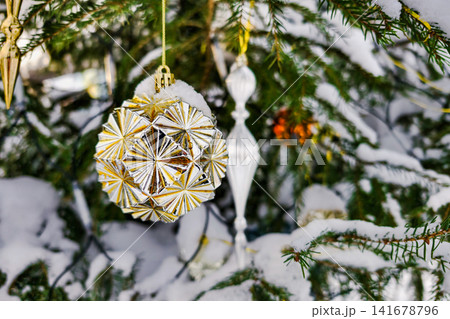 A decorated Christmas tree stands covered in snow during winter. Colorful ornaments hang from the branches as the holiday season arrives A decorated Christmas tree stands covered in snow during winter. Colorful ornaments hang from the branches as the holiday season arrives 141678796