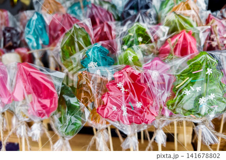 A market stand shows various candy treats shaped like Christmas trees. This display is filled with bright colors and is popular during the holiday season A market stand shows various candy treats shaped like Christmas trees. This display is filled with bright colors and is popular during the holiday season 141678802