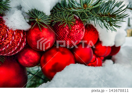 A Christmas tree is full of red ornaments at a location covered in snow. People celebrate the holidays by decorating and enjoying the festive atmosphere A Christmas tree is full of red ornaments at a location covered in snow. People celebrate the holidays by decorating and enjoying the festive atmosphere 141678811