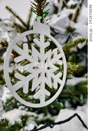 A Christmas tree is decorated with ornaments and lights. Snow is covering the ground and branches. The atmosphere is festive and joyful A Christmas tree is decorated with ornaments and lights. Snow is covering the ground and branches. The atmosphere is festive and joyful 141678846