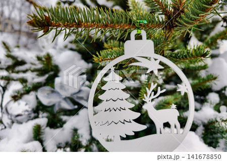 A Christmas tree is adorned with decorations in a snowy landscape. The scene shows a festive ornament featuring a tree and a deer A Christmas tree is adorned with decorations in a snowy landscape. The scene shows a festive ornament featuring a tree and a deer 141678850