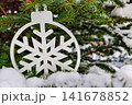 A Christmas tree is decorated with a snowflake ornament and surrounded by snow. This scene captures the spirit of New Year festivities in winter 141678852