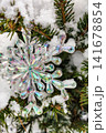 A shiny ornament hangs from a pine branch covered in snow, representing the spirit of the New Year and Christmas celebration 141678854