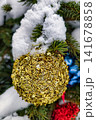 A Christmas tree ornament is covered in gold while snow falls around it. The scene captures winter festivities in a holiday setting 141678858
