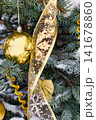 A Christmas tree is decorated with golden ornaments and ribbons. Snow is present on the tree branches, creating a festive atmosphere during the holiday season 141678860