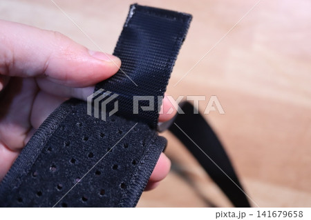 Close-up of Hand Holding Black Perforated Strap Close-up of Hand Holding Black Perforated Strap 141679658