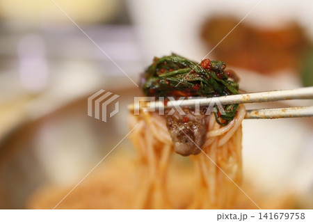 Chopsticks Holding Spicy Noodles with Leafy Greens Chopsticks Holding Spicy Noodles with Leafy Greens 141679758