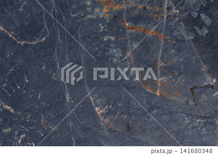 Rugged abstract texture of an outdoor slate rock surface. Industrial dark grey background with organic orange rust deposits and mineral veins Rugged abstract texture of an outdoor slate rock surface. Industrial dark grey background with organic orange rust deposits and mineral veins 141680348