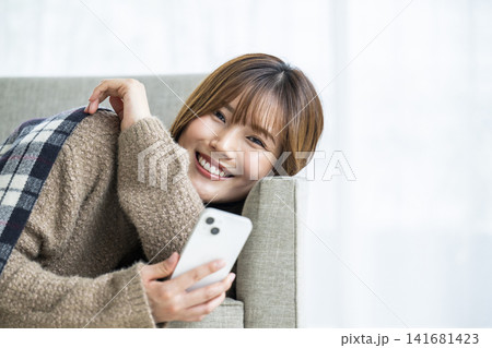 部屋でスマホを操作する若い女性 部屋でスマホを操作する若い女性 141681423