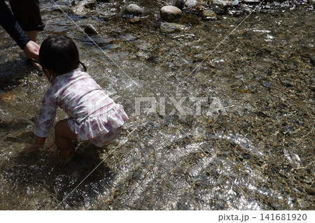 川で水遊びする女の子の後ろ姿。浅い流れと砂利の河原。 川で水遊びする女の子の後ろ姿。浅い流れと砂利の河原。 141681920