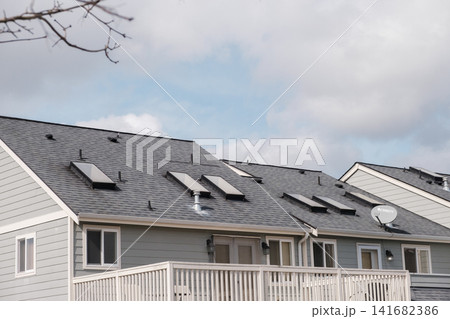 A close-up of grey townhouse roofs featuring multiple skylights, a satellite dish, and white railings. - March, 09 2026, Milton WA, USA 141682386