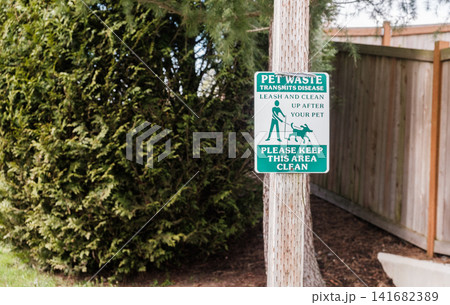 A green pet waste warning sign mounted on a wooden post next to a fence - March, 09 2026, Milton WA, USA A green pet waste warning sign mounted on a wooden post next to a fence - March, 09 2026, Milton WA, USA 141682389