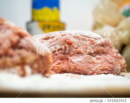 A piece of minced chicken in flour. Meat after the meat grinder. Cooking cutlets. Minced meat close-up. 141682431