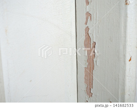 Part of an old door. White paint is coming off the wood. Surface with peeling paint. 141682533
