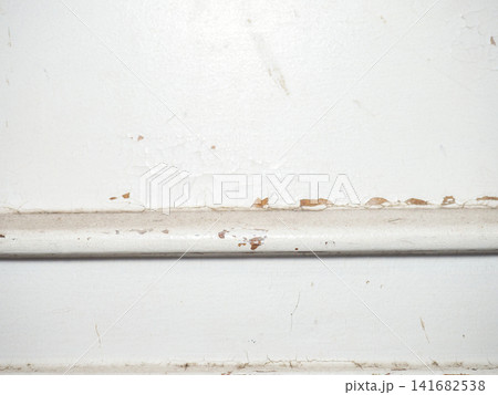 Part of an old door. White paint is coming off the wood. Surface with peeling paint. Part of an old door. White paint is coming off the wood. Surface with peeling paint. 141682538