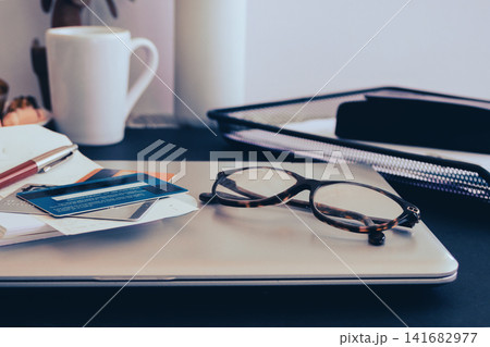 Workspace with a laptop, credit cards, glasses, and a pen on a desk, representing a professional environment for business, financial planning, online transactions, and focused work Workspace with a laptop, credit cards, glasses, and a pen on a desk, representing a professional environment for business, financial planning, online transactions, and focused work 141682977