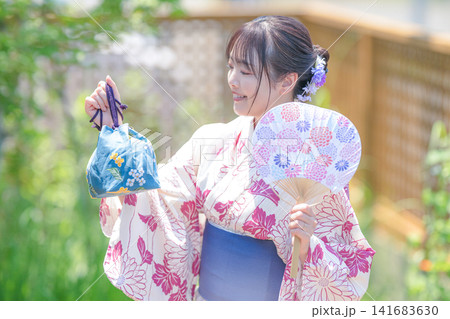 うちわと巾着を手にする浴衣女性、夏の装い うちわと巾着を手にする浴衣女性、夏の装い 141683630