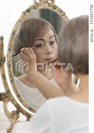 鏡の前でメイクをするシニア女性 鏡の前でメイクをするシニア女性 141683798