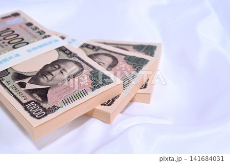 布の上に置かれた1万円の札束 布の上に置かれた1万円の札束 141684031