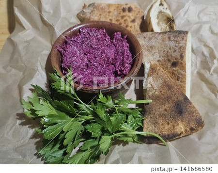 Traditional beetroot appetizer garnished with fresh parsley and served with warm flatbread on parchment paper as a complimentary restaurant starter 141686580