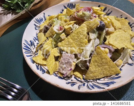 Fresh Mexican style chicken salad with tortilla chips, corn, tomatoes and creamy dressing served on decorative ceramic plate 141686581