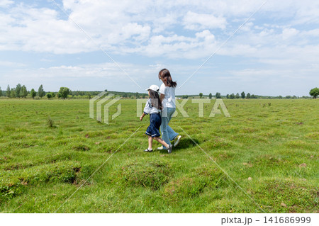Two young girls holding hands and walking across a vast vibrant green meadow. Two young girls holding hands and walking across a vast vibrant green meadow. 141686999