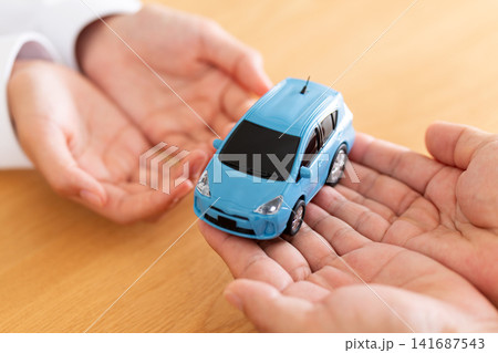 自動車の模型を手渡す男女の手元 141687543