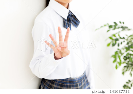 指を4本立てる制服姿の女子中学生 141687732