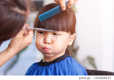 Cute Asian Little Girl Getting Haircut at Home With Different Emotions 141688031