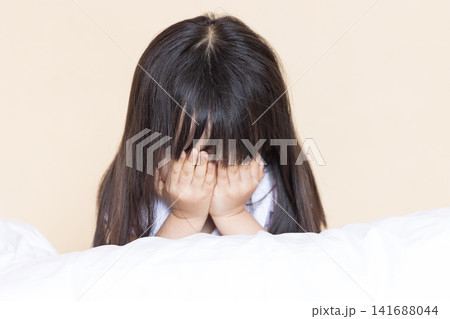 Cute Asian Little Girl Feeling Sad and Unhappy on Bed Indoors, Emotional Child Hugging Pillow in Warm Cozy Bedroom Cute Asian Little Girl Feeling Sad and Unhappy on Bed Indoors, Emotional Child Hugging Pillow in Warm Cozy Bedroom 141688044