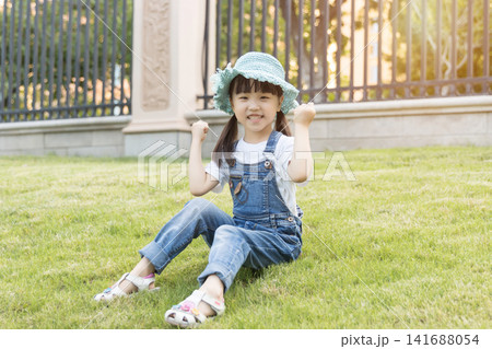 Happy Asian Little Girl Playing on Green Grass in Summer Park Happy Asian Little Girl Playing on Green Grass in Summer Park 141688054