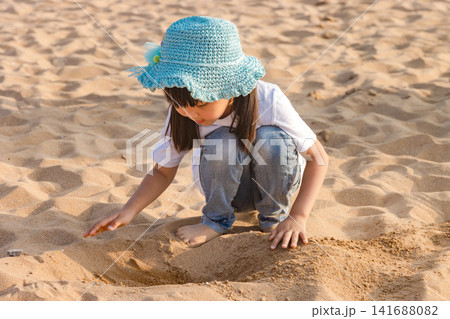 Asian Little Girl Playing With Sand on Beach During Summer Vacation Asian Little Girl Playing With Sand on Beach During Summer Vacation 141688082