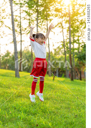 Enthusiastic young goalkeeper wearing gloves and catching a soccer ball in mid-air at the park. Enthusiastic young goalkeeper wearing gloves and catching a soccer ball in mid-air at the park. 141688265