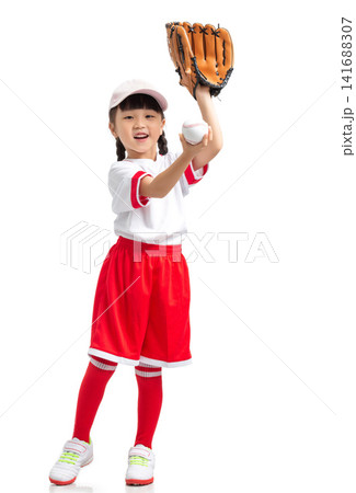 Full length view of a young baseball player raising her gloved hand against a white backdrop. Full length view of a young baseball player raising her gloved hand against a white backdrop. 141688307
