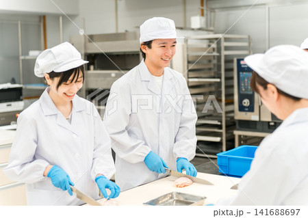 鶏肉を調理するコックコート姿の男女スタッフ（調理師・料理人・生鮮市場・食品加工） 141688697