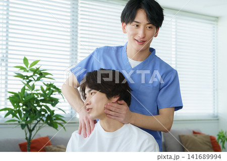施術をする若い日本人男性整体師と若い日本人の男性患者 141689994