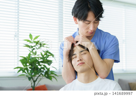 施術をする若い日本人男性整体師と若い日本人の男性患者 141689997