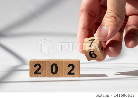 Hand Holding Wooden Number Block to Change 2026 into 2027 New Year Concept Hand Holding Wooden Number Block to Change 2026 into 2027 New Year Concept 141690618