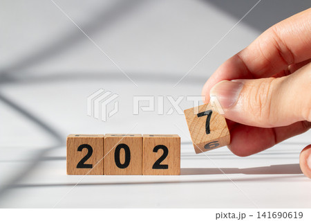Hand Holding Wooden Number Block to Change 2026 into 2027 New Year Concept Hand Holding Wooden Number Block to Change 2026 into 2027 New Year Concept 141690619