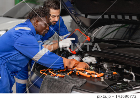 Professional EV Car Service, Male workers Electricity Vehicle Fix Maintenance in EV Garage workshop. 141690772