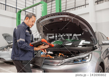 Professional EV Car Service, Male workers Electricity Vehicle Fix Maintenance in EV Garage workshop. Professional EV Car Service, Male workers Electricity Vehicle Fix Maintenance in EV Garage workshop. 141690802