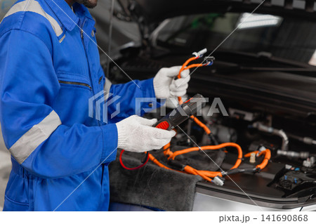 Professional EV Car Service, Male worker Electricity Vehicle Fix Maintenance in EV Garage workshop. 141690868
