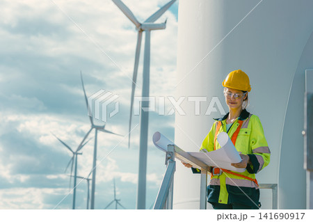 female engineer working outdoor with safety at wind turbines clean energy power station background. female engineer working outdoor with safety at wind turbines clean energy power station background. 141690917