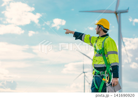 engineer male working outdoor with safety at wind turbines clean energy power station background. engineer male working outdoor with safety at wind turbines clean energy power station background. 141690920